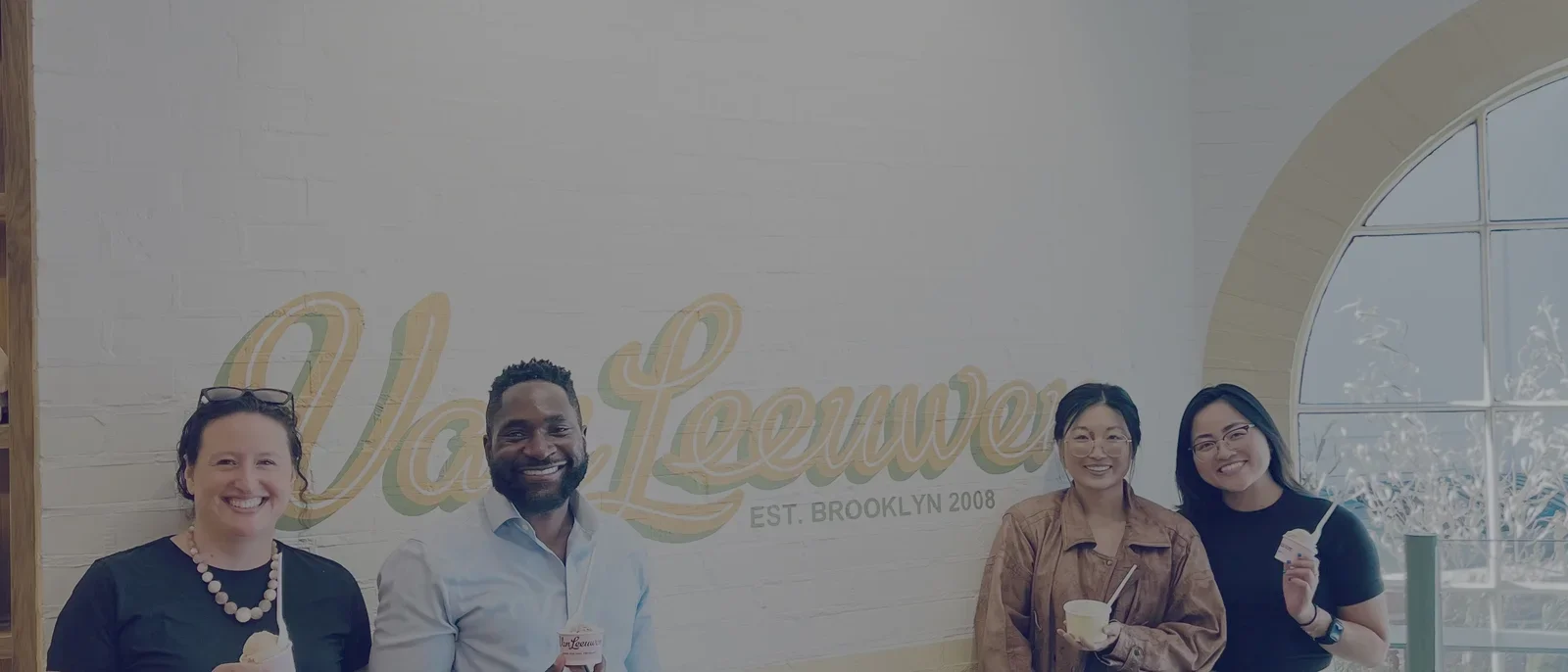 4 people in front of ice cream sign holding ice cream cones