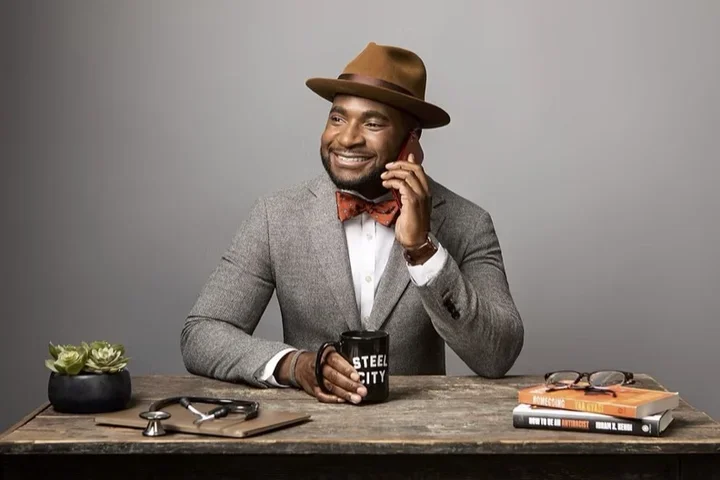 Man with hat smiling on the phone sitting at a table