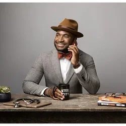 Man with hat smiling on the phone sitting at a table