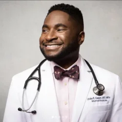 Man smiling with brown tie, stethescope, with white doctor's coat